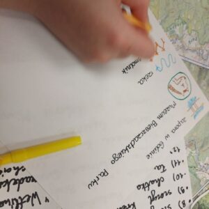 Zbliżenie na dłoń nanoszącą detale na mapę podczas zajęć