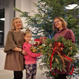 Uśmiechnięte uczestniczki warsztatów prezentujące gotowy, obfity wieniec.