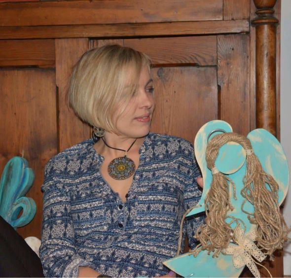 Maria Romanów, właścicielka Bieszczadzkiej Aniołomanii, trzyma drewnianą figurkę anioła. Ręcznie robiony prezent.