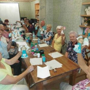 Grupa seniorów skupiona przy wspólnym stole podczas warsztatów rękodzieła