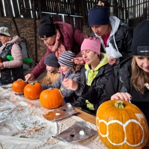 Uczestniczka warsztatów precyzyjnie malująca detale na dyniach