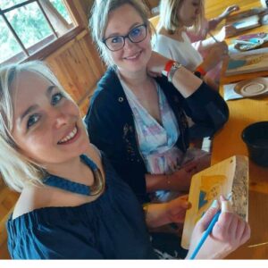 Uśmiechnięte uczestniczki warsztatów malarskich podczas wspólnej twórczości