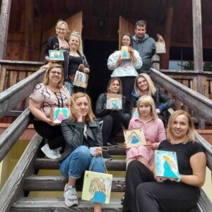 Grupa kobiet dumnie prezentująca własnoręcznie namalowane anioły na schodach