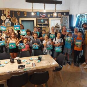 Uczestnicy warsztatów dumnie prezentujący swoje rękodzieło w pracowni