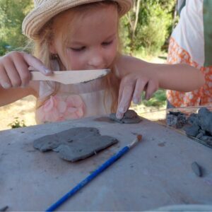 Uczestnicy warsztatów skupieni na rzeźbieniu w glinie przy wspólnym stole