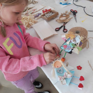 Zbliżenie na dłonie dziecka precyzyjnie wykańczającego drewnianego aniołka