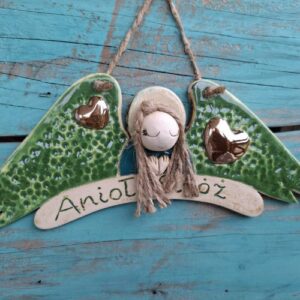Unikalny ceramiczny anioł stróż (30x17 cm) inspirowany naturą, wariant 'Leśna Nimfa'. Zdobiony motywami mchu i leśnej roślinności w odcieniach zieleni i brązu. Sznurkowe włosy i brązowa aureola. Rękodzieło.